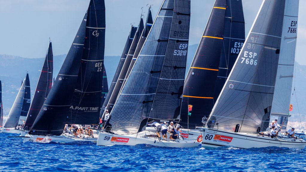 La 43ª Copa del Rey MAPFRE arranca con récord de participación y el estreno del Campeonato de Europa ORC Subtítulo: Más de 130 barcos de 24 países, incluidos el Aifos del Rey Don Felipe y el Teatro del Soho San Miguel, pelearán por la corona continental hasta el sábado en Palma Cuerpo de texto: Palma, 28 de julio de 2025 – El Real Club Náutico de Palma ya lo tiene todo listo para dar inicio mañana martes a la 43ª edición de la Copa del Rey MAPFRE, que este año vuelve a hacer historia al acoger por primera vez el Campeonato de Europa ORC. Hasta el próximo sábado, más de 130 equipos procedentes de 24 países competirán por un doble objetivo: coronarse campeones de la prestigiosa regata del Mediterráneo y conquistar el título continental en sus respectivas clases. El evento, que combina deporte y sociedad a partes iguales, arrancó hoy con la tradicional regata de entrenamiento oficial, aunque las inusuales condiciones de calma en la bahía impidieron completar el programa previsto. Entre los equipos que saltaron al agua estuvo el Aifos, patroneado por el Rey Don Felipe, quien volvió a entrenar junto a su tripulación en el campo de regatas, preparándose para luchar por su primer título europeo en la clase ABANCA ORC 0. En esa misma categoría competirá también el Teatro del Soho San Miguel, el TP52 de Javier Banderas, actual campeón de la Copa del Rey MAPFRE y uno de los grandes favoritos, con el respaldo de un palmarés que incluye cuatro victorias consecutivas (2021–2024) y títulos continentales previos. Esta flota reúne una decena de los barcos más veloces de la regata, ofreciendo un espectáculo asegurado en el campo de batalla náutico mallorquín. La clase Sail Racing ORC A será la más internacional, con 34 equipos de 16 países y una nómina de favoritos entre los que destacan el Estrella Damm del RCMT Punta Umbría, patroneado por el olímpico Luis Martínez Doreste; el Pez de Abril de José María Meseguer; y el Elena Nova del alemán Christian Plump. En Ubico ORC B, el podio de la pasada edición se vuelve a reunir con el argentino Katara, el italiano Guardamago y el español L’Immens, mientras que en la categoría Uber ORC C defenderá título el Fala Pouco de Andrés Manresa, reciente vencedor del Trofeo S.M. La Reina. Cada clase ORC disputará un máximo de ocho pruebas puntuables, dos de ellas en formato costero –una novedad en esta edición–, con recorridos de entre 10 y 12 horas a lo largo del litoral mallorquín, diseñados según las condiciones meteorológicas. Por su parte, la Balearia Women’s Cup reunirá 15 equipos femeninos en monotipos BluSail 24, que competirán en formato Round Robin desde el miércoles, con las seis mejores embarcaciones accediendo a una Medal Series final que decidirá las campeonas. Más allá del agua, el RCNP acoge un completo programa social con actividades para regatistas, patrocinadores e invitados: desde brunchs y cócteles como el tradicional Cóctel de Blanco del jueves, hasta conciertos y la esperada gala de entrega de premios el sábado en el Palacio de La Almudaina. La Copa del Rey MAPFRE vuelve a consolidarse como una cita de referencia en la vela internacional, combinando máxima exigencia deportiva con el inconfundible sello social que define esta histórica regata.